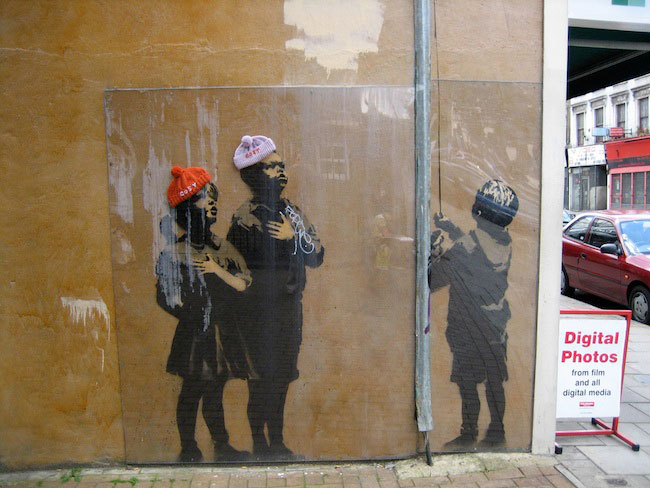 muurkunst van banksy met gebreide mutsen