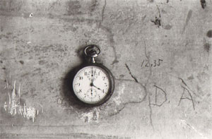 het horloge, maar kijk ook eens naar de muur...