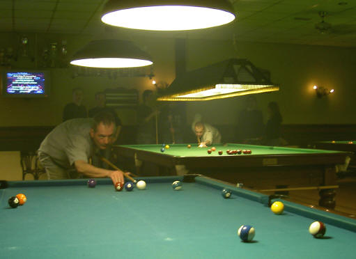de man op de achterste tafel speelt snooker...